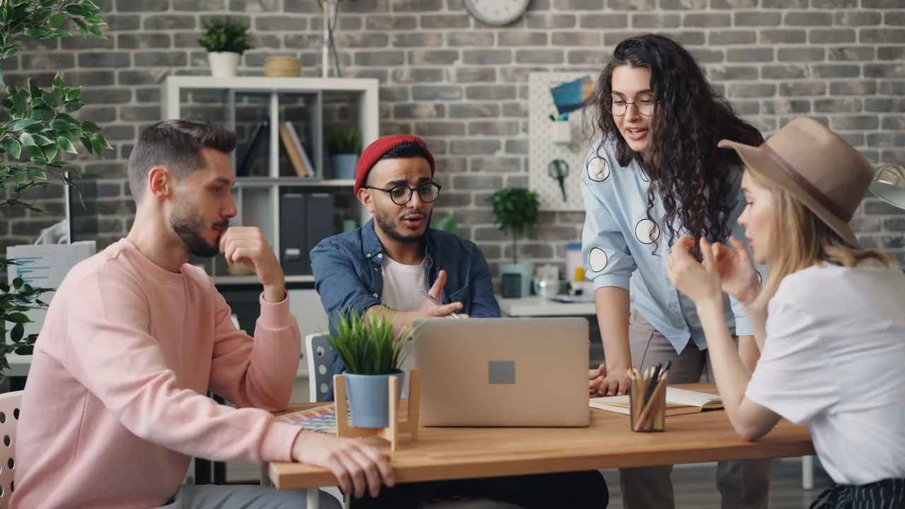 A group of people talking around a laptop.